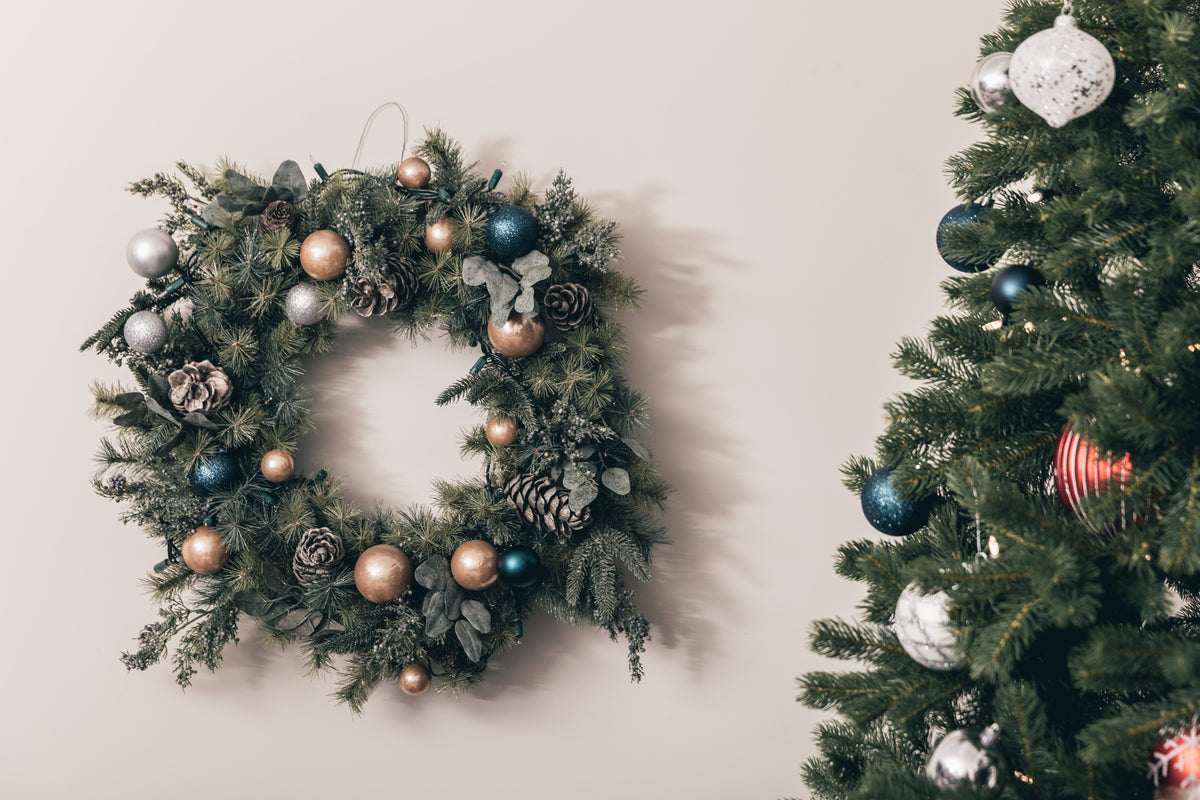 Couronne de Noël accrochée à côté d'un sapin décoré