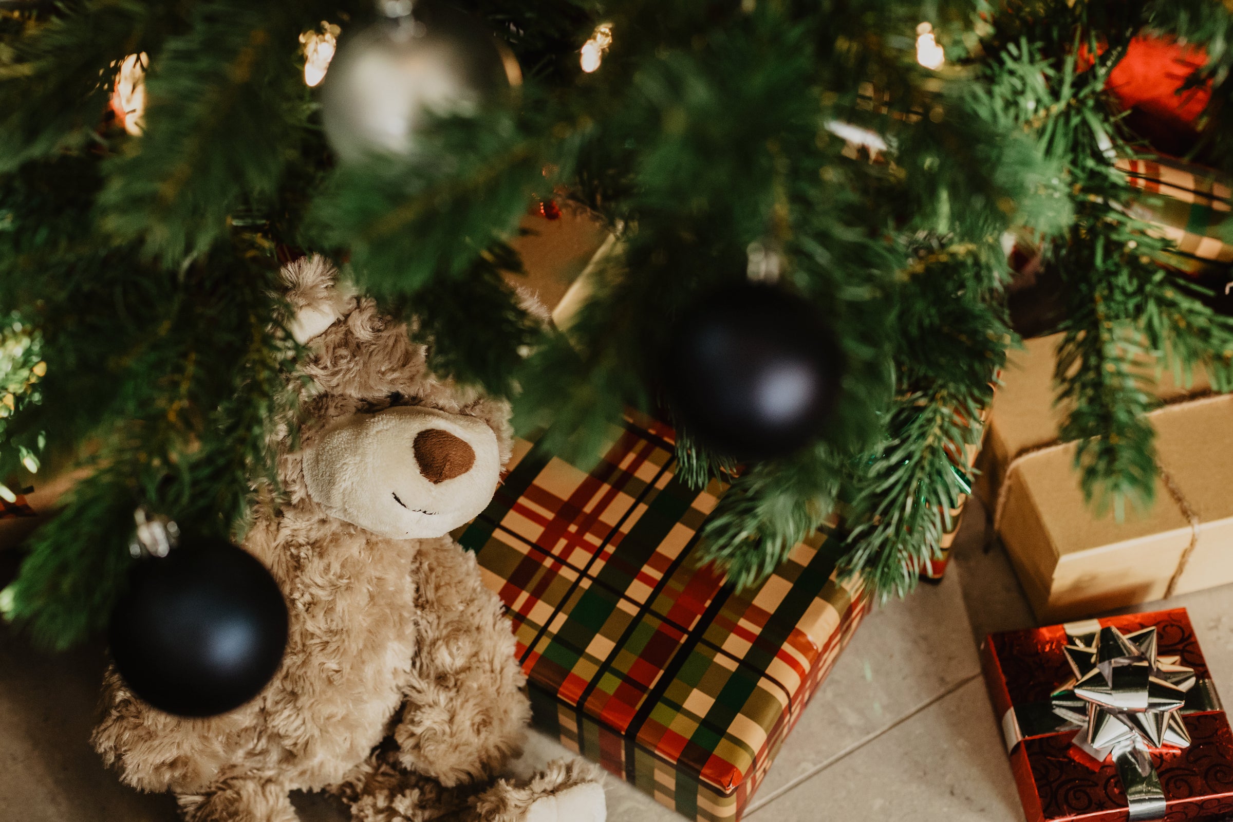 Cadeaux de Noël emballés et ourson sous le sapin décoré